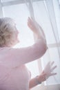 Senior attractive woman looking out of the window at home