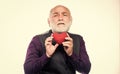 Senior bald head bearded man holding red toy heart in hands. Mature man with valentines heart. Heart problem and