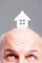 Senior balding man looking up at a model house Royalty Free Stock Photo