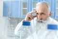 Senior bearded chemist in white coat in chemical laboratory