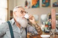 Senior bearded man drinking coffee sitting bar counter - Happy mature male having fun enjoying retired time Royalty Free Stock Photo