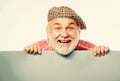 Senior bearded man peek out of banner place announcement. Advertisement shop. Pensioner grandfather in vintage hat hold Royalty Free Stock Photo