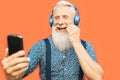 Senior bearded man taking selfie with mobile phone while listening favorite playlist with headphones Royalty Free Stock Photo