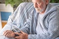 Senior bearded man using medical device to measure blood pressure, elder grandfather sitting at home on sofa Royalty Free Stock Photo