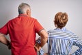 Senior beautiful couple standing together over isolated white background standing backwards looking away with arms on body Royalty Free Stock Photo