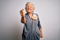 Senior beautiful grey-haired woman wearing casual dress standing over white background angry and mad raising fist frustrated and Royalty Free Stock Photo