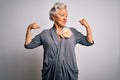 Senior beautiful grey-haired woman wearing casual dress standing over white background showing arms muscles smiling proud Royalty Free Stock Photo