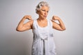 Senior beautiful grey-haired woman wearing casual summer dress over white background showing arms muscles smiling proud Royalty Free Stock Photo