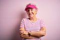 Senior beautiful sporty woman wearing sport cap standing over isolated pink background happy face smiling with crossed arms Royalty Free Stock Photo