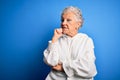 Senior beautiful sporty woman wearing white sweatshirt over isolated blue background with hand on chin thinking about question, Royalty Free Stock Photo