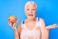 Senior beautiful woman with blue eyes and grey hair holding nachos potato chips celebrating achievement with happy smile and Royalty Free Stock Photo
