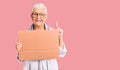 Senior beautiful woman with blue eyes and grey hair holding we need a change banner surprised with an idea or question pointing