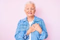 Senior beautiful woman with blue eyes and grey hair wearing casual denim jacket smiling with hands on chest with closed eyes and Royalty Free Stock Photo