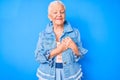 Senior beautiful woman with blue eyes and grey hair wearing casual denim style smiling with hands on chest with closed eyes and Royalty Free Stock Photo