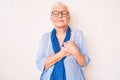 Senior beautiful woman with blue eyes and grey hair wearing casual sweater and scarf smiling with hands on chest, eyes closed with Royalty Free Stock Photo