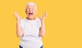 Senior beautiful woman with blue eyes and grey hair wearing casual white tshirt celebrating mad and crazy for success with arms Royalty Free Stock Photo