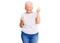 Senior beautiful woman with blue eyes and grey hair wearing casual white tshirt celebrating surprised and amazed for success with Royalty Free Stock Photo