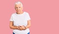 Senior beautiful woman with blue eyes and grey hair wearing casual white tshirt with hand on stomach because indigestion, painful Royalty Free Stock Photo