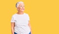 Senior beautiful woman with blue eyes and grey hair wearing casual white tshirt looking away to side with smile on face, natural Royalty Free Stock Photo