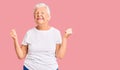 Senior beautiful woman with blue eyes and grey hair wearing casual white tshirt very happy and excited doing winner gesture with Royalty Free Stock Photo