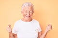 Senior beautiful woman with blue eyes and grey hair wearing classic white tshirt over yellow background very happy and excited Royalty Free Stock Photo