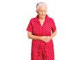 Senior beautiful woman with blue eyes and grey hair wearing a red summer dress with hand on stomach because indigestion, painful Royalty Free Stock Photo