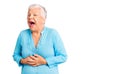 Senior beautiful woman with blue eyes and grey hair wearing summer dress with hand on stomach because nausea, painful disease Royalty Free Stock Photo