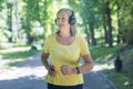 Senior beautiful woman in headphones running in the park, morning jogging, active lifestyle, listening to music. Feels good, Royalty Free Stock Photo