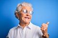 Senior beautiful woman wearing elegant shirt and glasses over isolated blue background smiling with happy face looking and Royalty Free Stock Photo