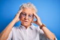 Senior beautiful woman wearing elegant shirt and glasses over isolated blue background suffering from headache desperate and