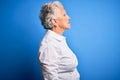 Senior beautiful woman wearing elegant shirt standing over isolated blue background looking to side, relax profile pose with Royalty Free Stock Photo