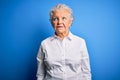 Senior beautiful woman wearing elegant shirt standing over isolated blue background smiling looking to the side and staring away Royalty Free Stock Photo