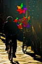 Senior on bicycle with colorful pinwheels in sunset light