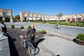 Senior with bicycle walk through Imam Square with historical buildings