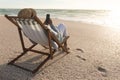 Senior biracial woman sitting on chair using mobile phone while relaxing at beach during sunset