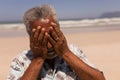 Senior black man with hands on face standing on beach