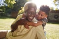 Senior black man sitting on grass, embraced by his grandson Royalty Free Stock Photo