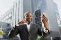 A senior black man in a suit is standing outside a business center and talking on the phone via video call in headphones Royalty Free Stock Photo