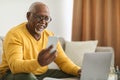 Senior Black Man Using Smartphone And Laptop Working Online Indoors Royalty Free Stock Photo