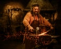 Senior blacksmith forging the molten metal on the anvil in smithy Royalty Free Stock Photo