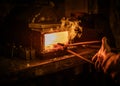 Senior blacksmith heats item before forging in smithy Royalty Free Stock Photo