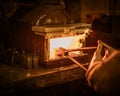 Senior blacksmith heats item before forging in smithy Royalty Free Stock Photo