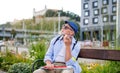 Senior blind man with smartphone sitting on bench in park in city. Royalty Free Stock Photo