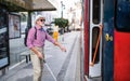 Senior blind man with white cane getting on public transport in city.