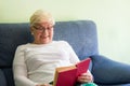 Senior blond woman with eyeglasses reading funny book