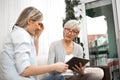 A senior blonde woman has a tablet in her hand while a young woman explains how to use the internet, social networks and online Royalty Free Stock Photo