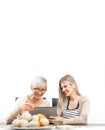 A senior blonde woman is sitting in the dining room with a young woman at the table. In front of them is a tablet computer, and a Royalty Free Stock Photo