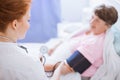 Senior with blood pressure monitor on her arm and young intern at hospital Royalty Free Stock Photo