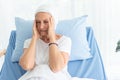 Senior breast cancer patient woman wearing a headscarf laying in bed, two hands grasped the head like headache, cancer concept Royalty Free Stock Photo