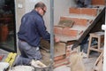 Senior bricklayer building a ceramic wood effect staircase in a home.